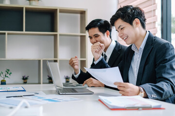 Two successful young Asian businessman working together in a modern office.