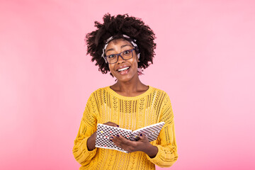 Attractive african american woman holding notebook. Young woman with glasses holding open textbook and smiling at camera. Education concept