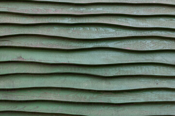 closeup of green weathered wood wall on playground with wave cut