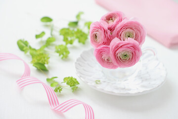 Obraz na płótnie Canvas Bouquet of pink ranunculus flowers in glass cup. ピンクのラナンキュラス