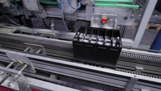 Automatic line for the assembly of car batteries. The black batteries move and collect on the conveyor belt.