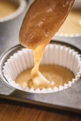 Woman filling muffin molds with a spoon.