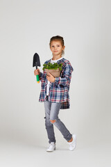 Little girl watering plants in a flower pot on studio background. the child dreams of becoming a...