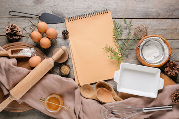 Notebook with ingredients for Christmas bakery and kitchen utensils on wooden background