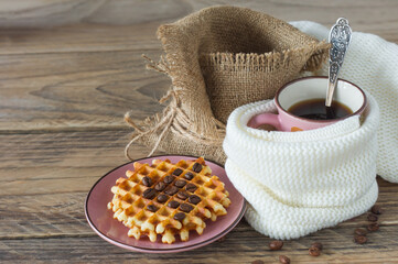 cup of freshly brewed americano coffee with belgian waffles on wooden table. coffee beans on light wooden table, rustic style, homemade.