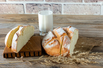 freshly baked bread on wooden gray kitchen table with glass of milk, homemade pastry.