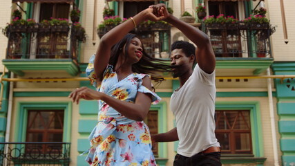Happy afro dancers curling in latino dance in city. Couple dancing on street - obrazy, fototapety, plakaty