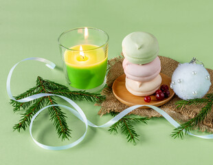 christmas composition with homemade pastel multi color zephyr in round shape, green candle and fir branches