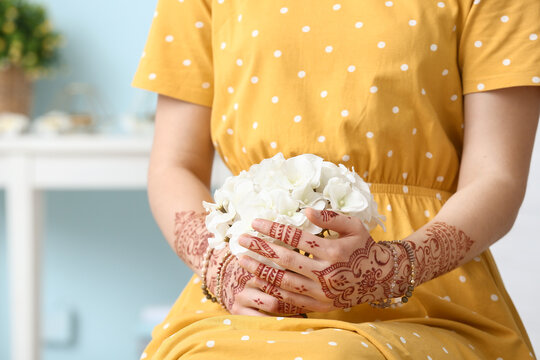 Beautiful woman with henna tattoo on her hands and flowers at home
