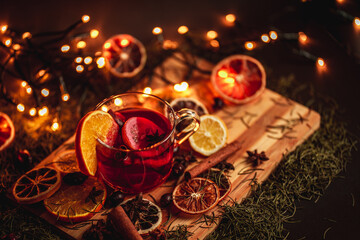 Christmas mulled wine, Drink with dried fruits and berries, Winter hot tea in a glass and spices on a wooden background. - obrazy, fototapety, plakaty