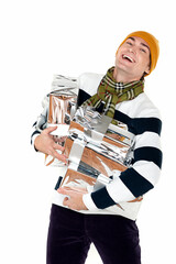 A handsome adult man in a striped jumper is holding several gifts in silver wrapping and laughing. Isolate on white. New Year advertising concept.