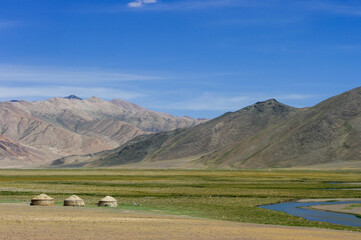 Mountain landscape with river and Kyrgyz nomadic yurts on summer pasture along high-altitude Pamir Highway near Murghab, Gorno-Badakshan, Tajikistan