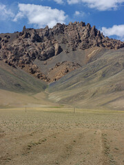 Fototapeta na wymiar Vertical landscape view of spectacular rock formations along high-altitude Pamir Highway near Murghab, Gorno-Badakshan, Tajikistan