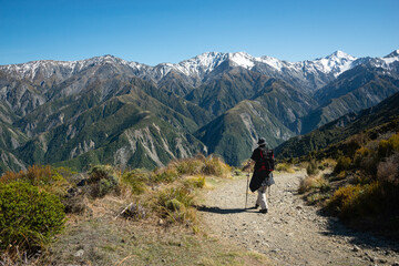 Fototapeta na wymiar Hiking Mt Fyffe track with snow-capped mountain peaks in the background, Kaikoura, South Island, New Zealand