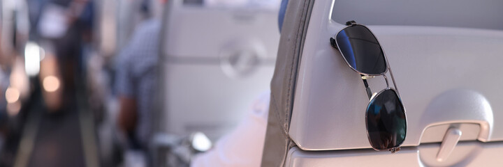 Sunglasses are placed on the passenger seat on plane. Summer vacation and travel concept