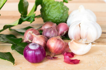 garlic ,red onion slice,lime leaf herbal vegetarian with knife on chopping block prepare to cook on tabla white