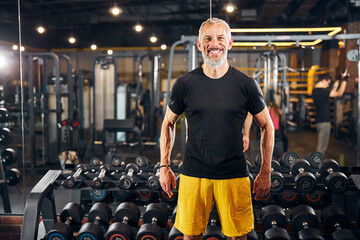Joyous personal trainer standing at the gym