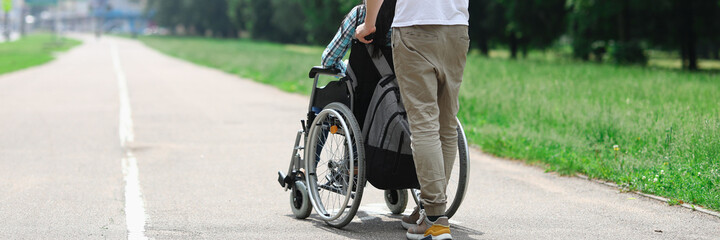 Man rolls wheelchair with girl down street. Relationship with a disabled person and walking together concept