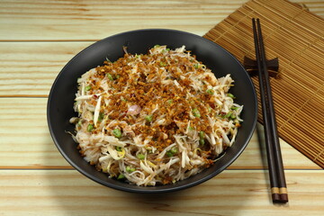 Spicy salad of rice noodle mixed with fresh bean sprouts, sliced long bean and topping with crispy fish meat on the plate. 