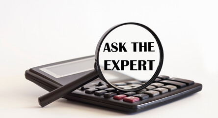 Focused on ASK THE EXPERT concept. Magnifier glass with text on calculator. Business concept