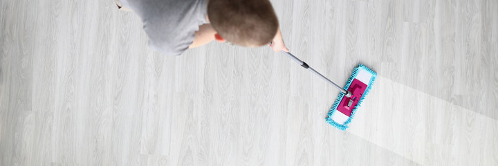 Man washes floor with mop on light floor. Helping husband with housework concept