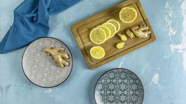 Ginger, honey, lemon and lime herbal tea preparation with high levels of Vitamin C, boosting the immune system. Top view, blue table surface. Stop motion animation.
