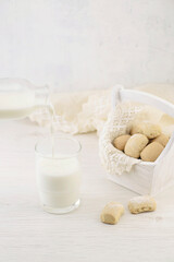 Milk is poured from a bottle into a glass. A basket of homemade cookies on a white wooden table. Top view