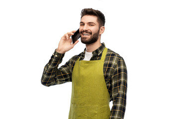 Fototapeta premium gardening, farming and people concept - happy smiling male gardener or farmer in apron calling on smartphone over white background