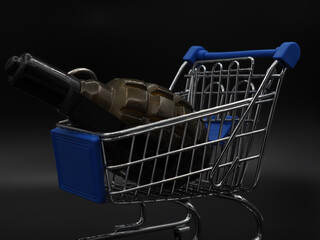 The concept of crisis. A green hand grenade in a shopping cart on a dark, black background.