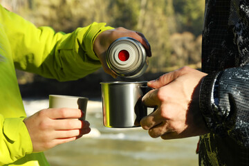 Naklejka premium Woman pouring coffee from a thermos into a cup of man