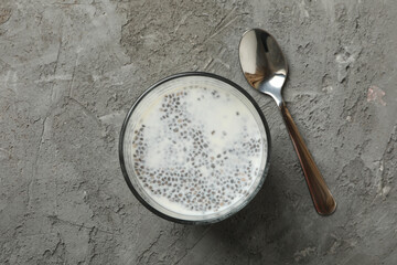 Spoon and glass with chia pudding on gray background