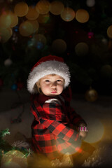 a child in red clothes is sitting waiting for the new year. the concept of celebrating Christmas at midnight. holiday costume