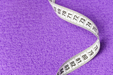 White measuring tape on a purple background.