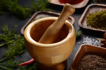 Wooden spice mortar and spices on dark background