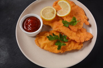 Two chicken breaded schnitzel with lemon on plate