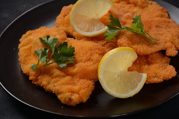 Two chicken breaded schnitzel with lemon on plate