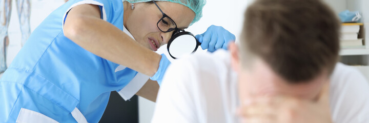 Practitioner doctor with magnifying glass in his hand examines rectum of man patient portrait....