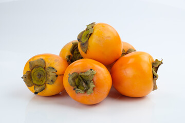 Eine Menge, ein Haufen tropisch-exotischer Kaki Früchte (lat.: Diospyros kaki) vor einem weißen Hintergrund