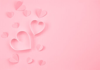 Paper cut hearts on pastel pink background. Composition for Valentine's Day, postcard. Flat lay, top view, copy space.