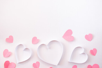 Paper cut hearts on pastel pink background. Composition for Valentine's Day, postcard. Flat lay, top view, copy space.