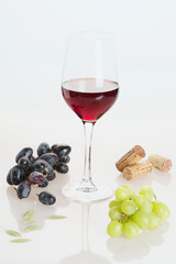 Verre remplie du vin avec des raisins sur la table