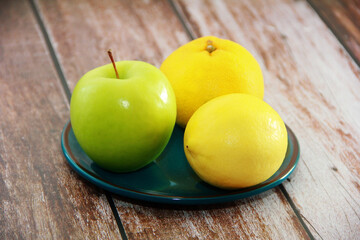 green apple and yellow lemon and tangerine on a decorative plate