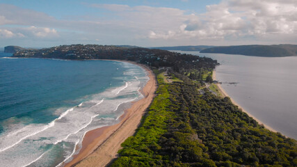 Palm Beach, Australia. Beautiful, narrow beach line, ocean waves sand and green vegetation.
