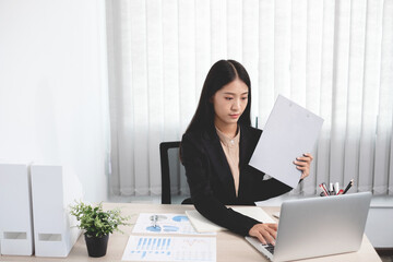 Asian businesswomen sit at their desks and calculate financial graphs showing results about their investments, plan a successful business growth process in the office