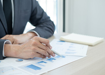 The businessman hand sits at their desks and calculates financial graphs showing the results of their investments planning the process of successful business growth