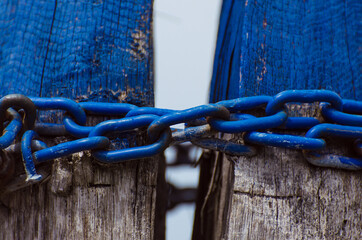 Una catena blu unisce due pali di legno - obrazy, fototapety, plakaty