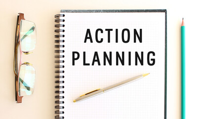 Notepad with text ACTION PLANNING on a white background, near glasses and pencil.