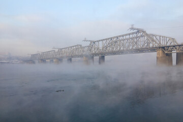 Bridge hidden in the fog. Winter morning on Yenisei river, Siberia