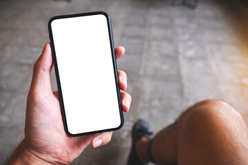 Mockup image of a hand holding and showing mobile phone with blank white screen in cafe