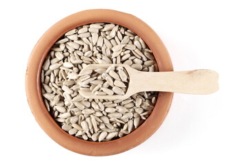 Peeled sunflower seeds and wooden spoon in clay bowl isolated on white background, top view
